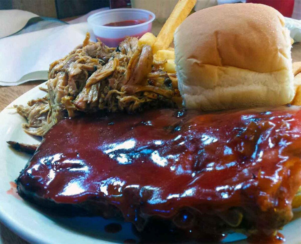 Plate of ribs, barbecue, fries and a dinner roll