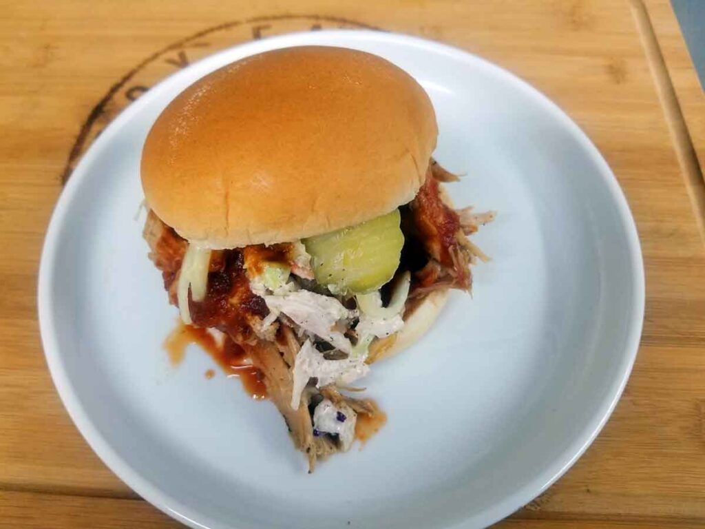 BBQ sandwich with slaw and a pickle on a plate