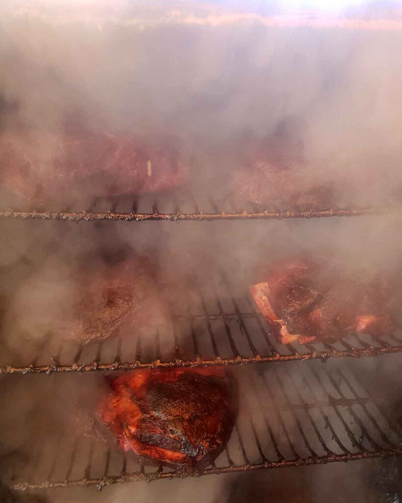 Inside of a smoky smoker with Boston butts peeking through