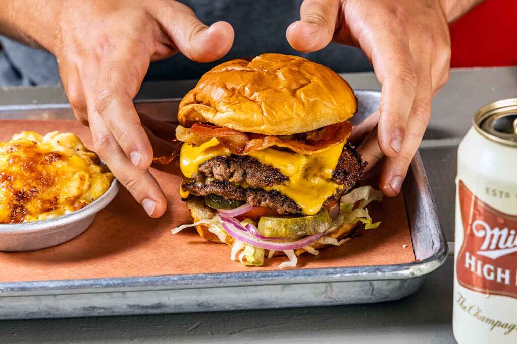Closeup of hands reaching to pick up a delicious looking hamburger