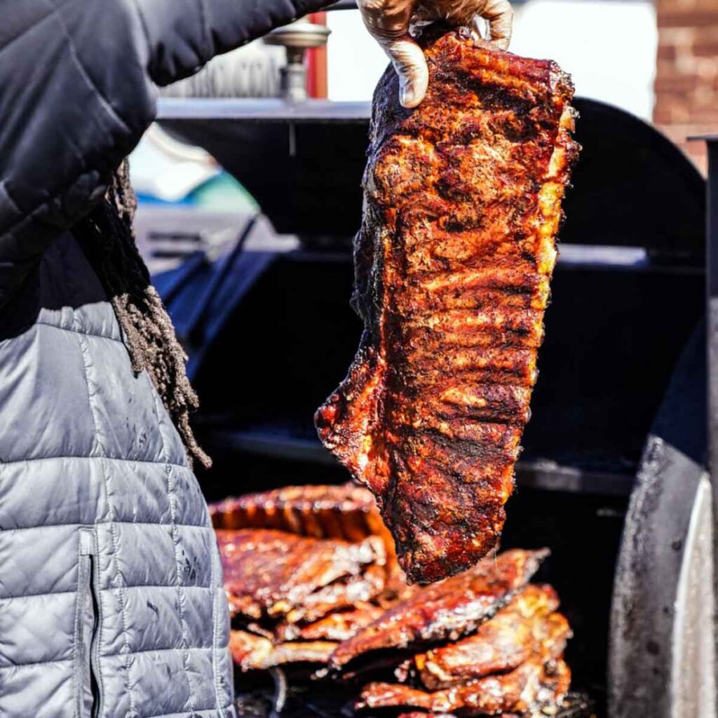 Pitmaster holding up rack of ribs.