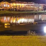 Exterior of Sheltons Smoking Butts BBQ at night lit up view from across pond
