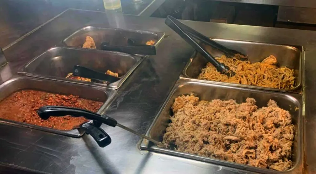 Two kinds of barbecue along with beans and two other (not visible) options on buffet.