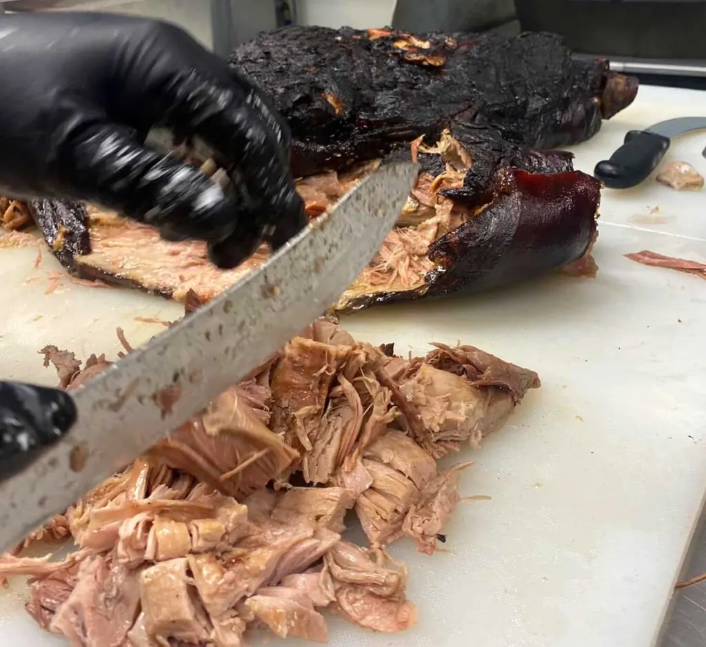 Closeup of barbecue being chopped on cutting board.