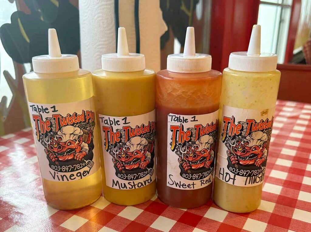 Four bottles, one of vinegar and three BBQ sauces