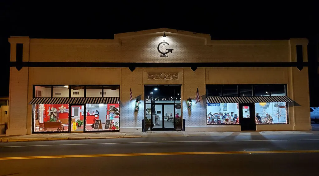 Exterior of G Brand BBQ at night with interior illuminated through the windows.