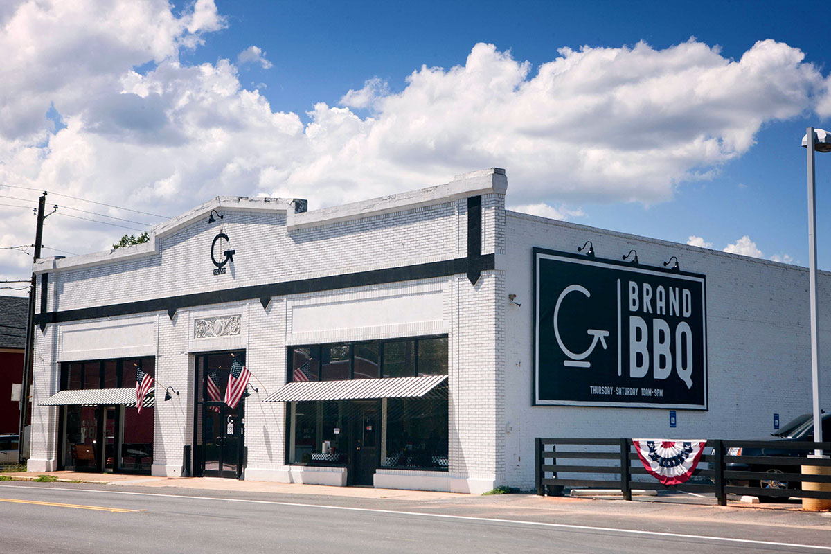 Exterior shot of G Brand BBQ showing both the side and front with logo on building's side.
