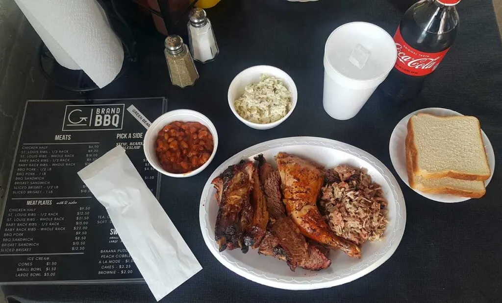 Plate of meats with sides and drink on table.