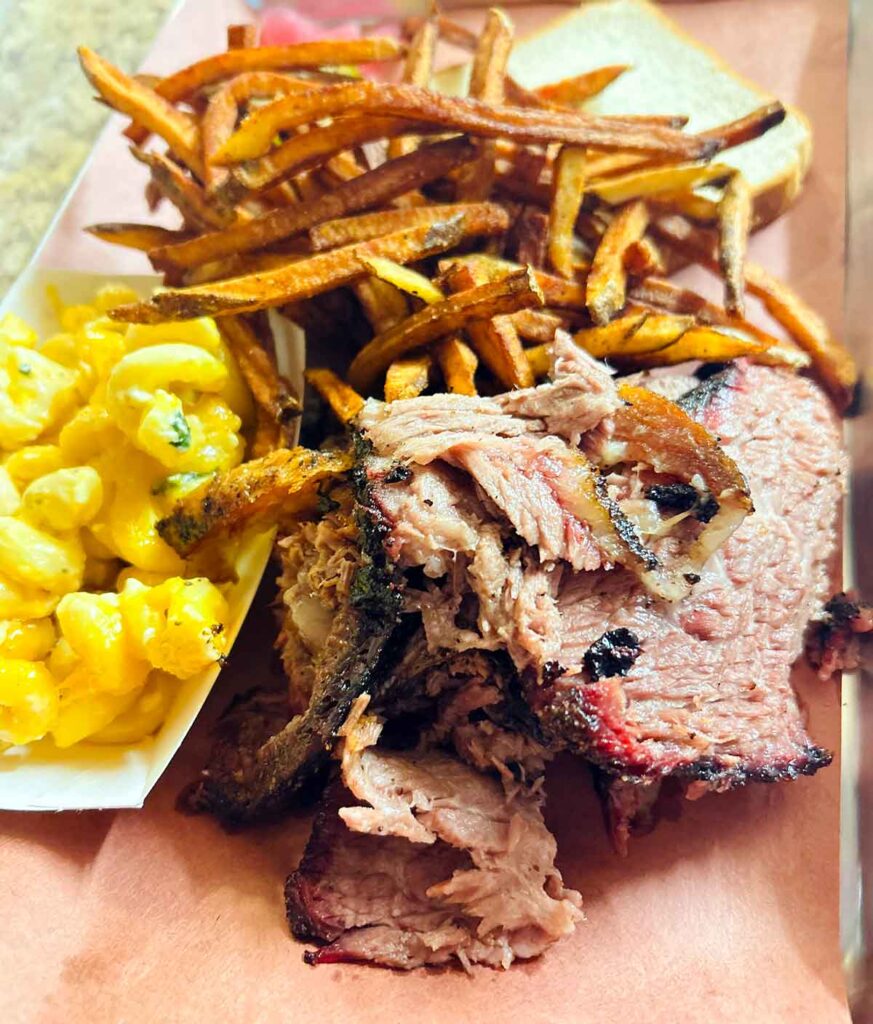 Brisket slices on tray with Mac and cheese and golden fries.