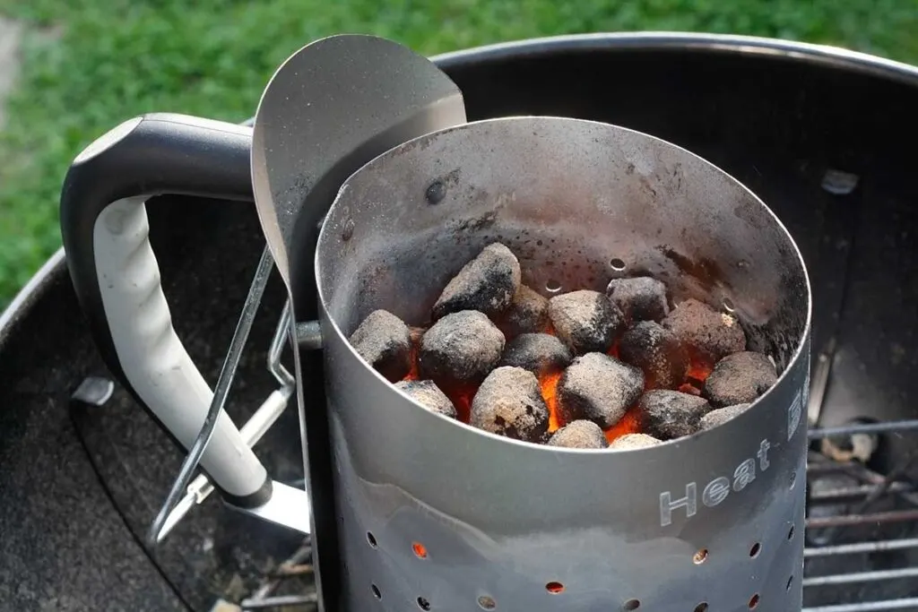 Closeup of a new chimney with nice handle and heat shield, red coals glowing inside.