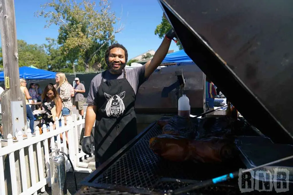 Marvin Ross of Peculiar Pig opens a pit to reveal a whole hog.