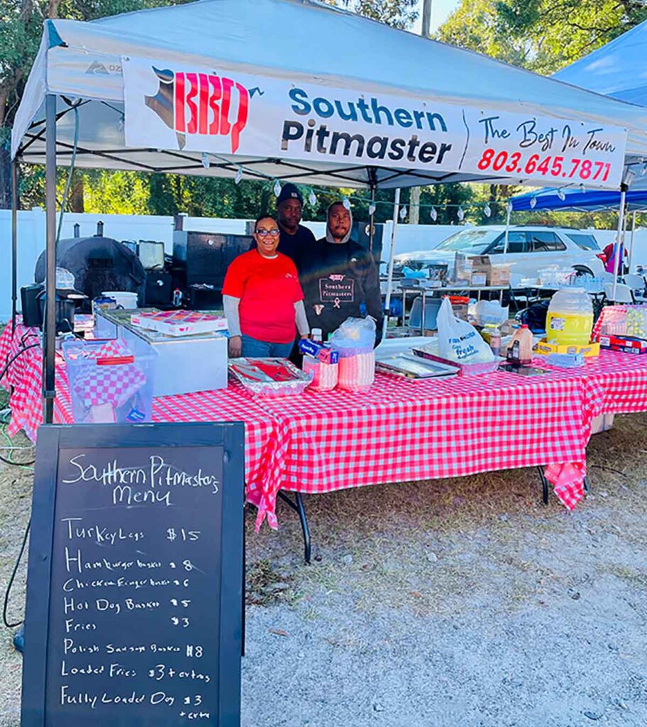 BBQ pitmaster tent selling smoked meat plates to festival goers.