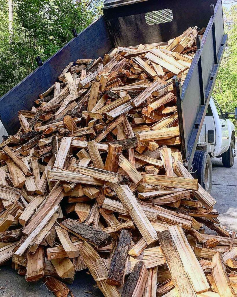 Firewood being dumped from the back of a dump truck.