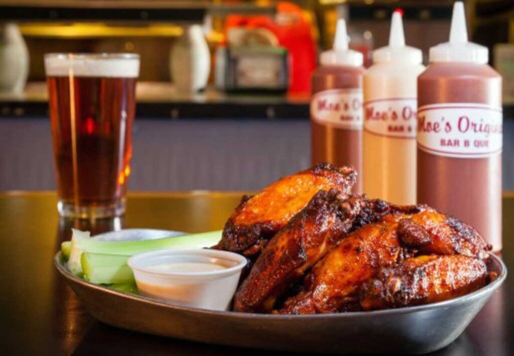 Wings on tray with beer and sauces in background.