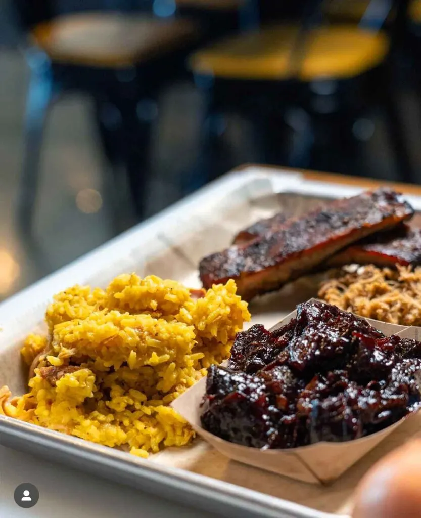 Tray with yellow rice, burnt ends, ribs, and pulled pork bbq.