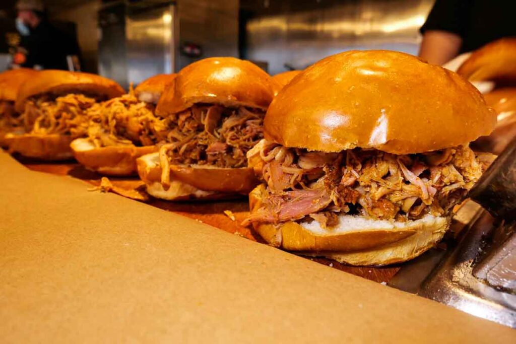 Several pulled pork sandwiches on full-size buns with generous portions of meat.