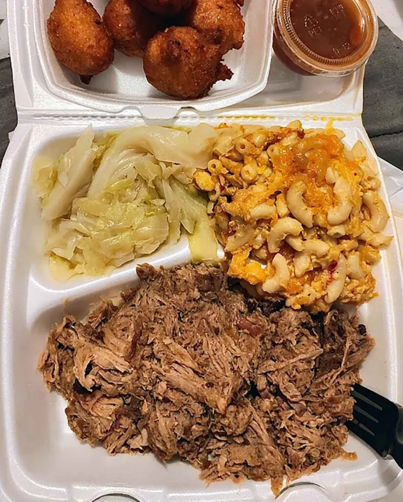 Styrofoam tray with bbq, mac and cheese, and stewed cabbage.