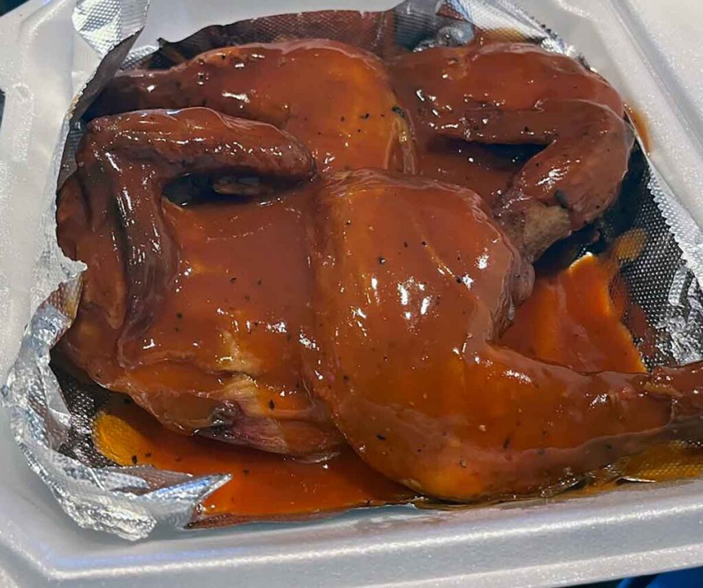 Takeout plate piled high with heavily sauced chicken quarters.