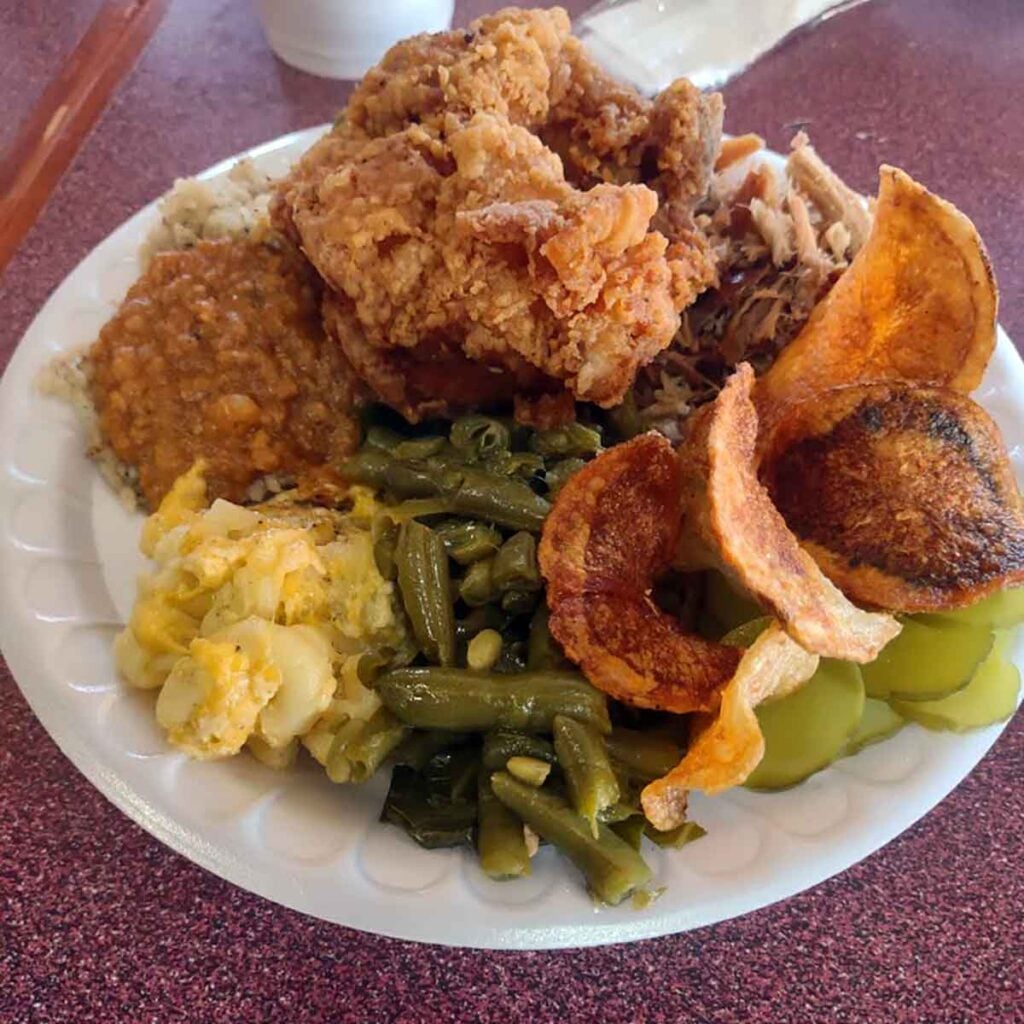 Plate of fried chicken, hash over rice, and sides.