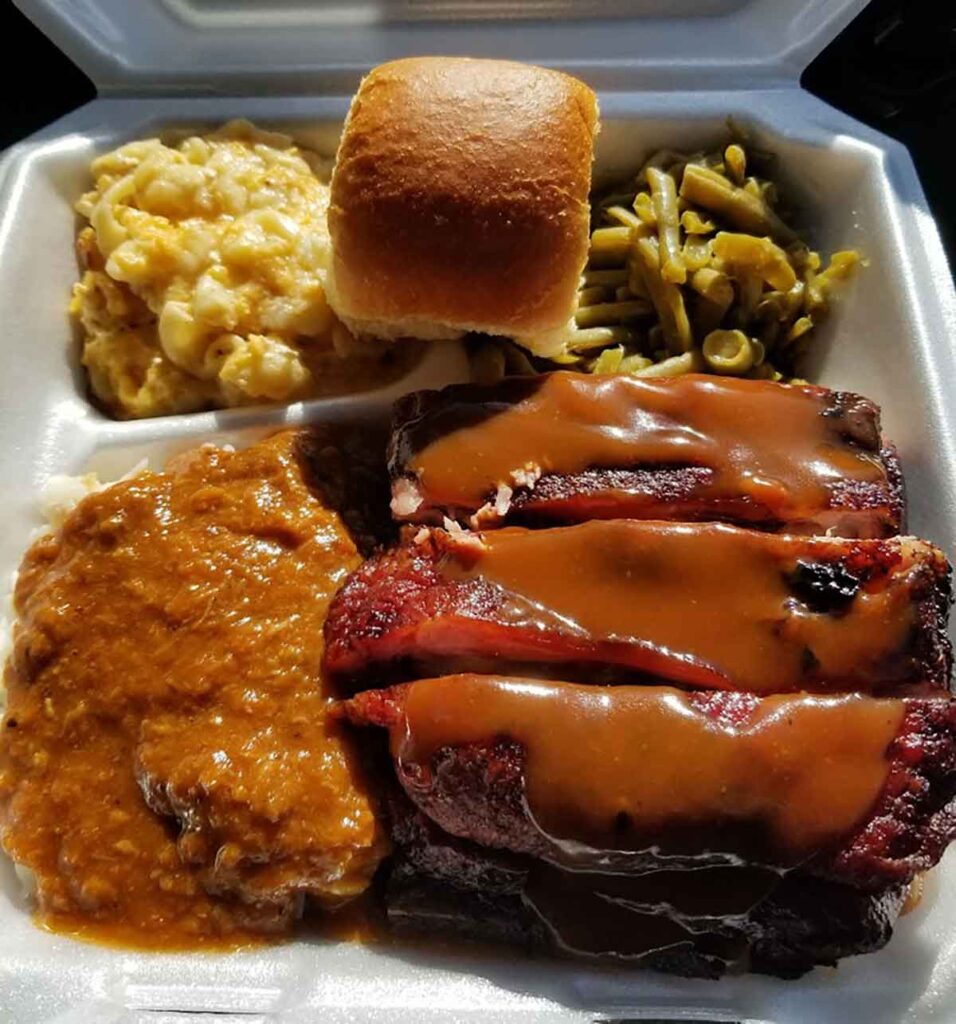 Takeout tray with sauced ribs, hash and rice, Mac and cheese and more.