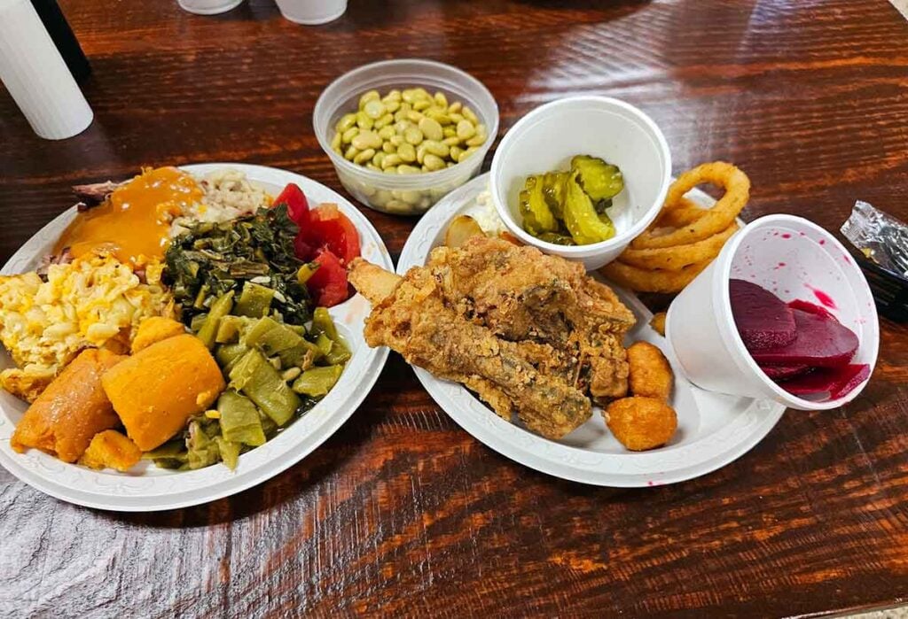 Two plates with sides and fried chicken.