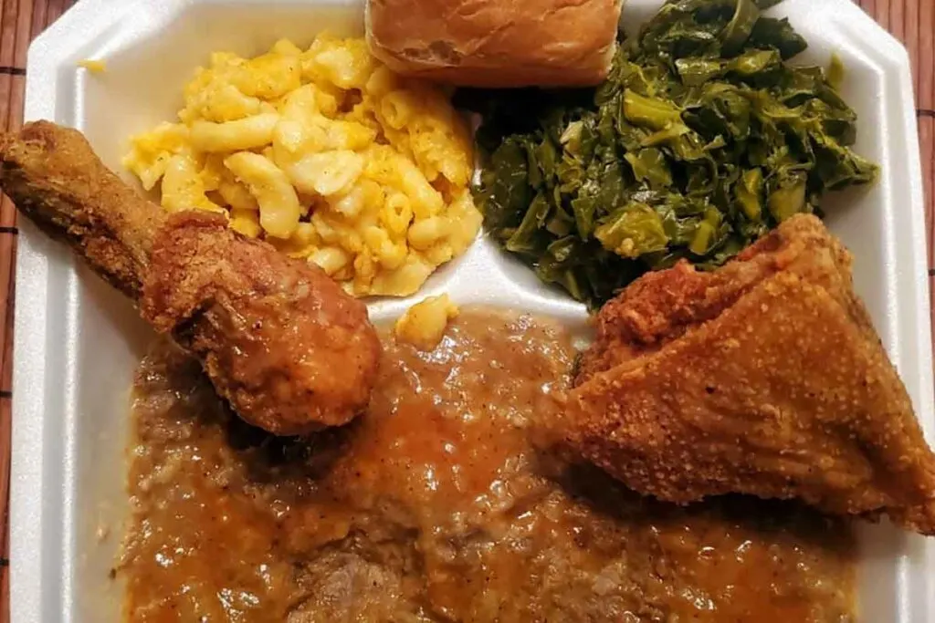 Container with fried chicken, hash, collards, Mac and cheese with a dinner roll from Big Ts.