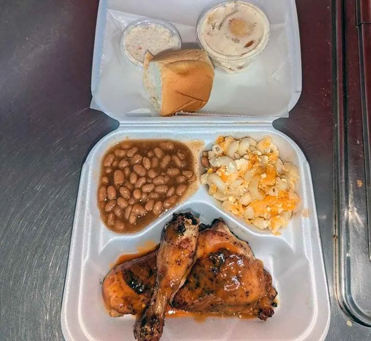 BBQ chicken and sides in takeout tray.