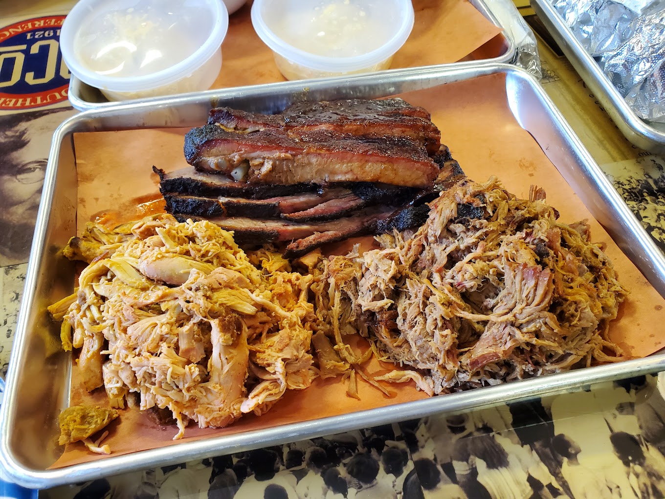 Metal tray with ribs, pulled pork, and pulled chicken.