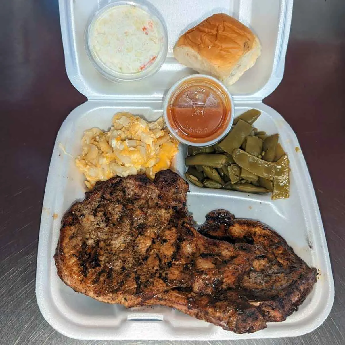 Steak and sides in takeout tray.