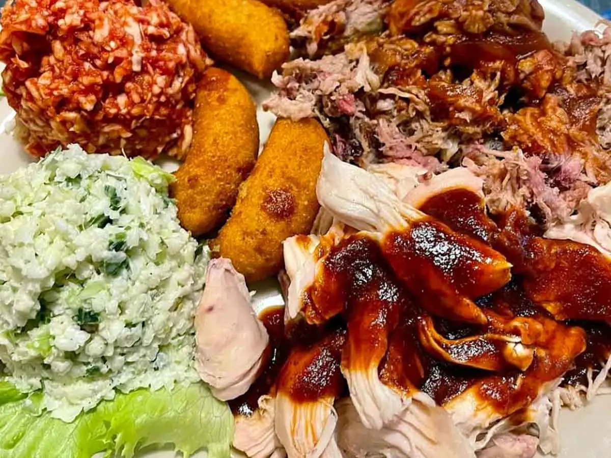 BBQ plate with pork, chicken, red slaw, regular slaw, and hushpuppies.