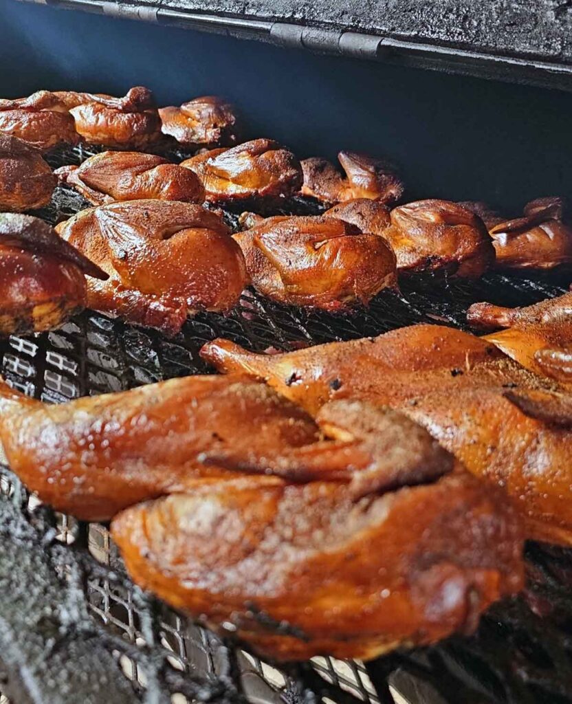 Rows of golden chicken halves on smoker.