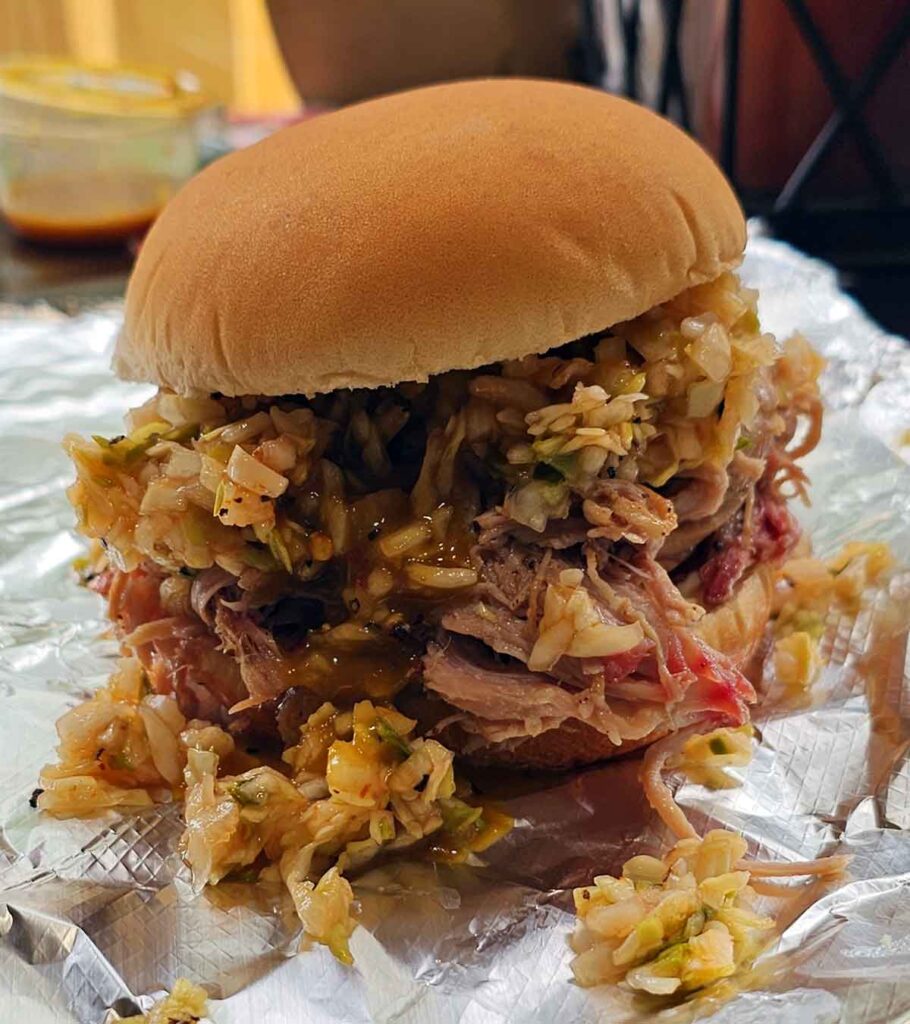 Pulled pork sandwich topped with slaw, on hamburger bun.