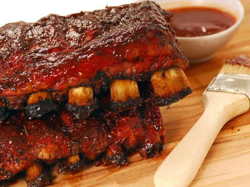 Smoked ribs beside brush and sauce.