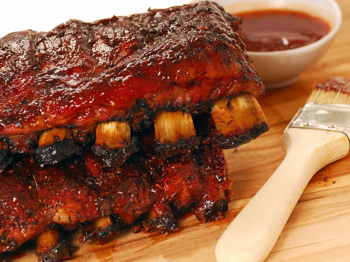 Smoked ribs beside brush and sauce.