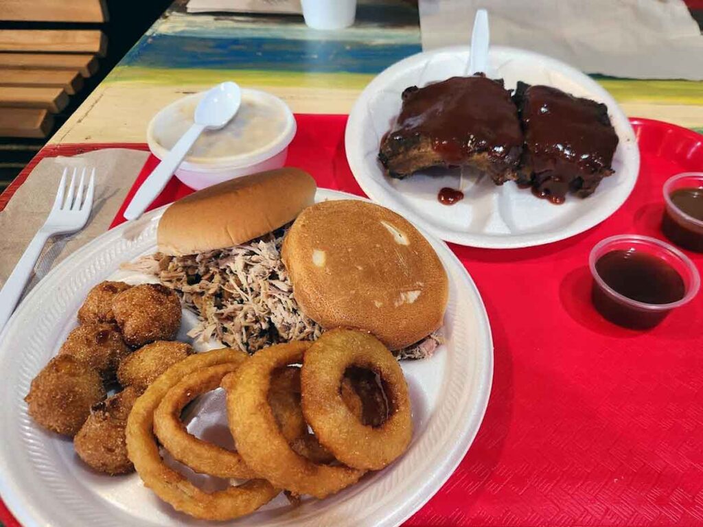 BBQ sandwich with ribs, onion rings and hush puppies.