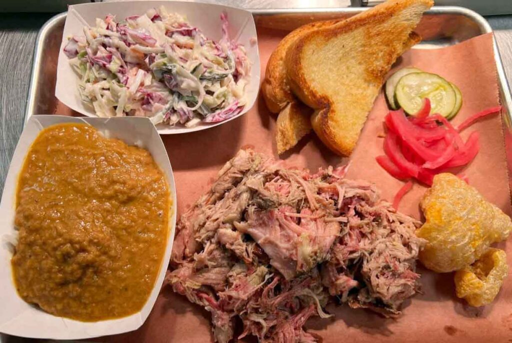 Pulled pork plate with hash, slaw, bread, and pickles.