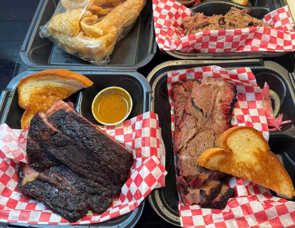 Takeout trays with ribs, brisket, pork and sides.