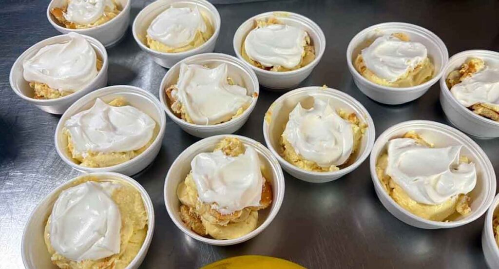 Several containers of banana pudding topped with whipped cream.