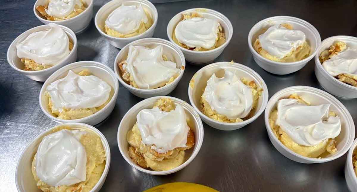 Several containers of banana pudding topped with whipped cream.