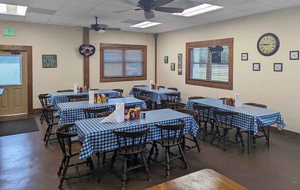 Interior of Crossroads BBQ with several long tables covered in blue gingham table cloths.