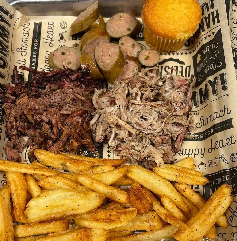 Platter with brisket, pork, sausage, and sides.