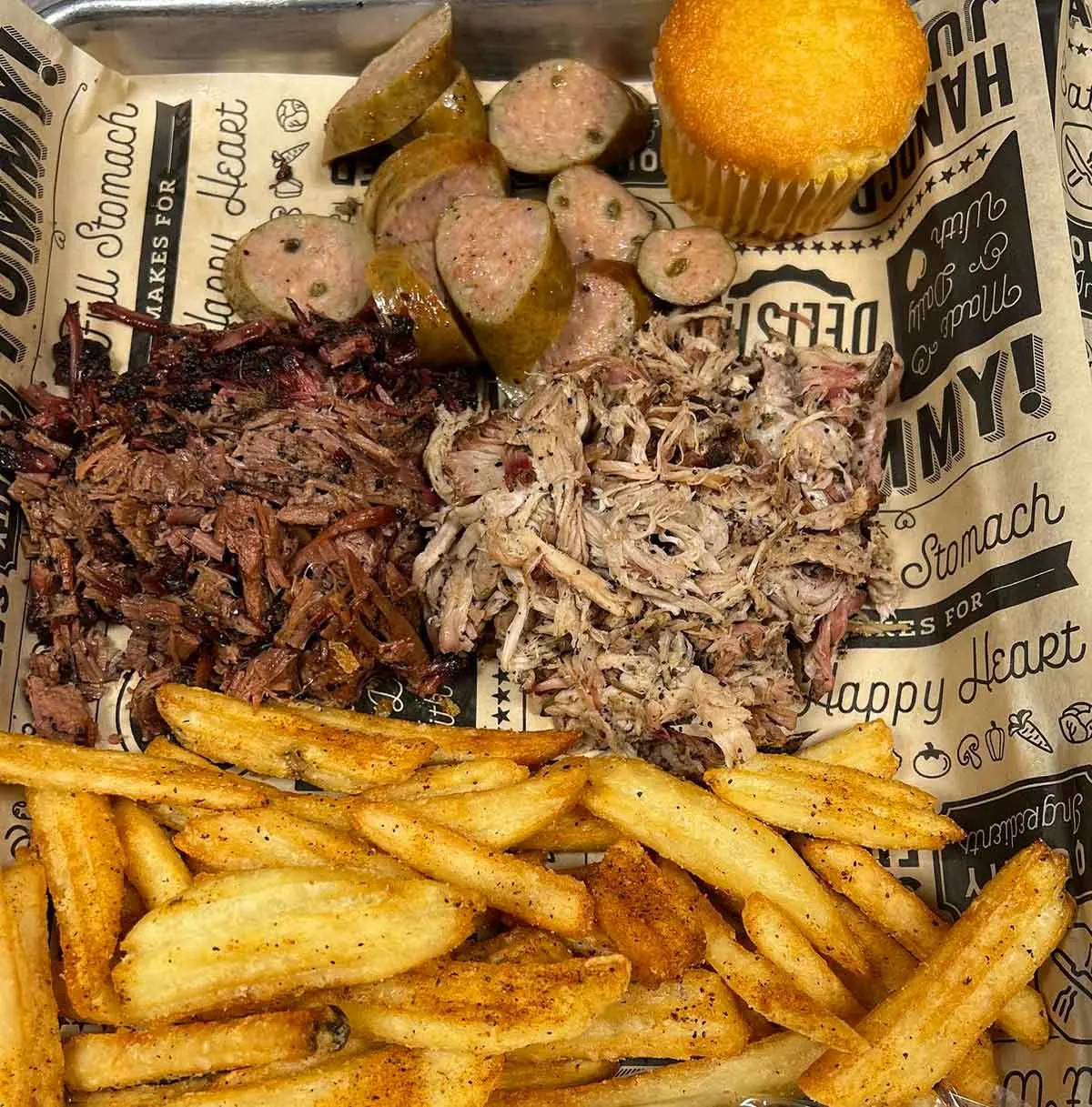 Platter with brisket, pork, sausage, and sides.