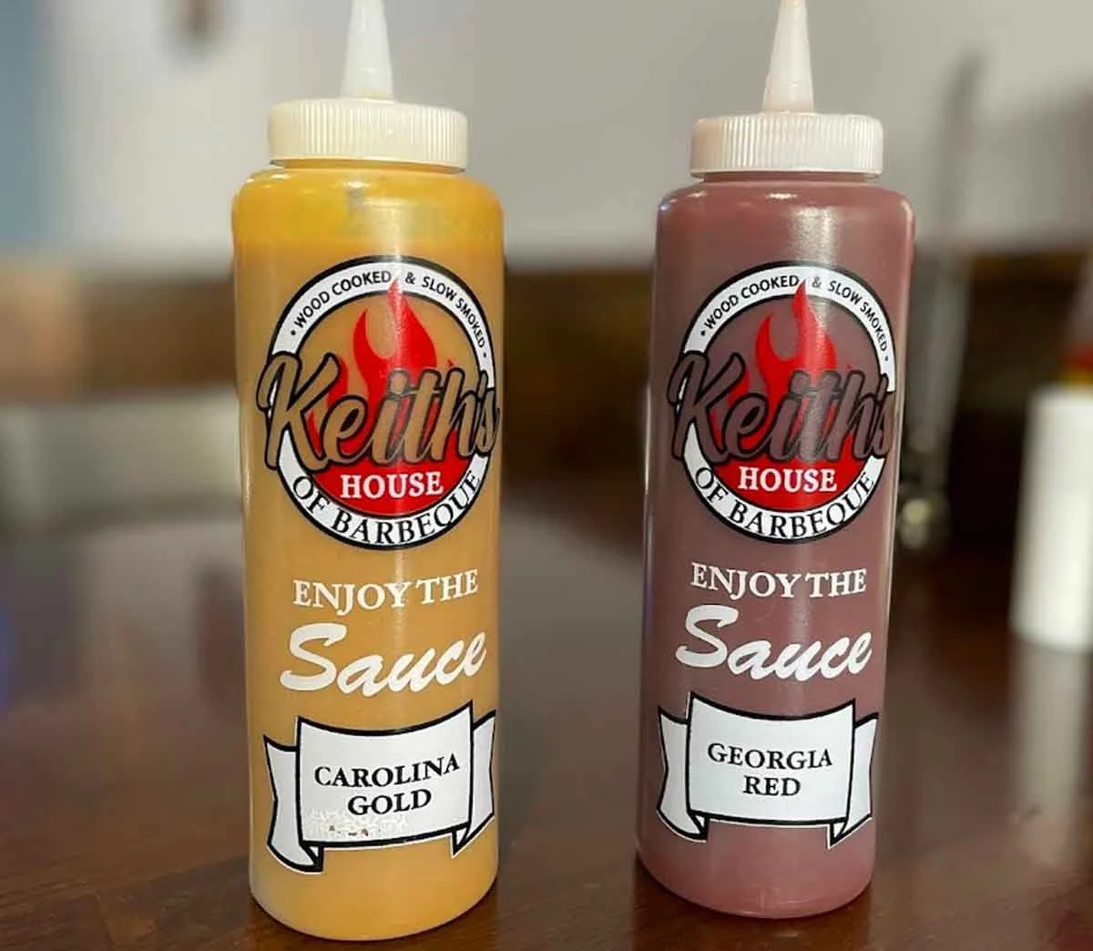Mustard and Red sauces in bottles on table.