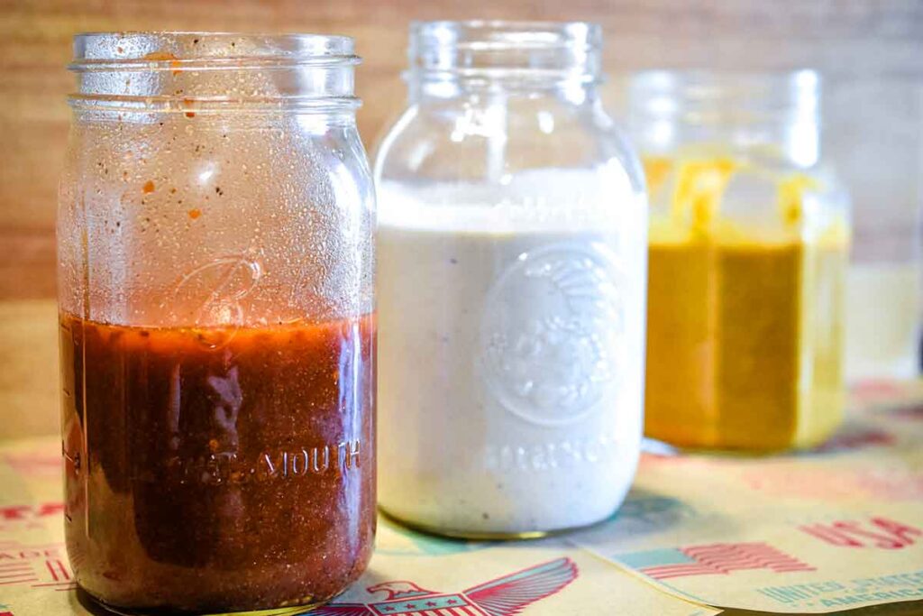 Mason jars filled with various sauces offered by Moohogz Craft BBQ.