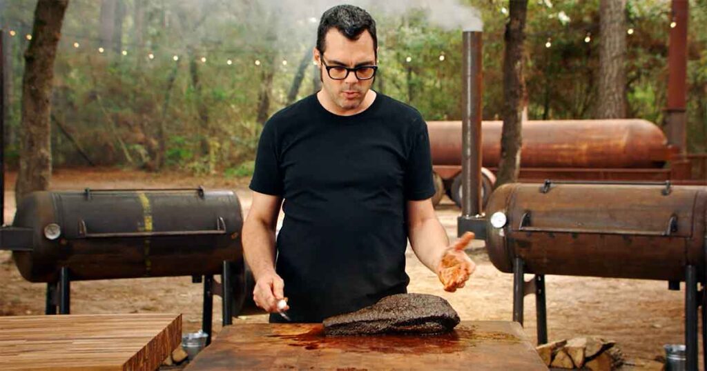 Aaron Franklin standing in front of a table with brisket.
