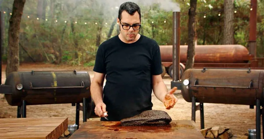 Aaron Franklin standing in front of a table with brisket.