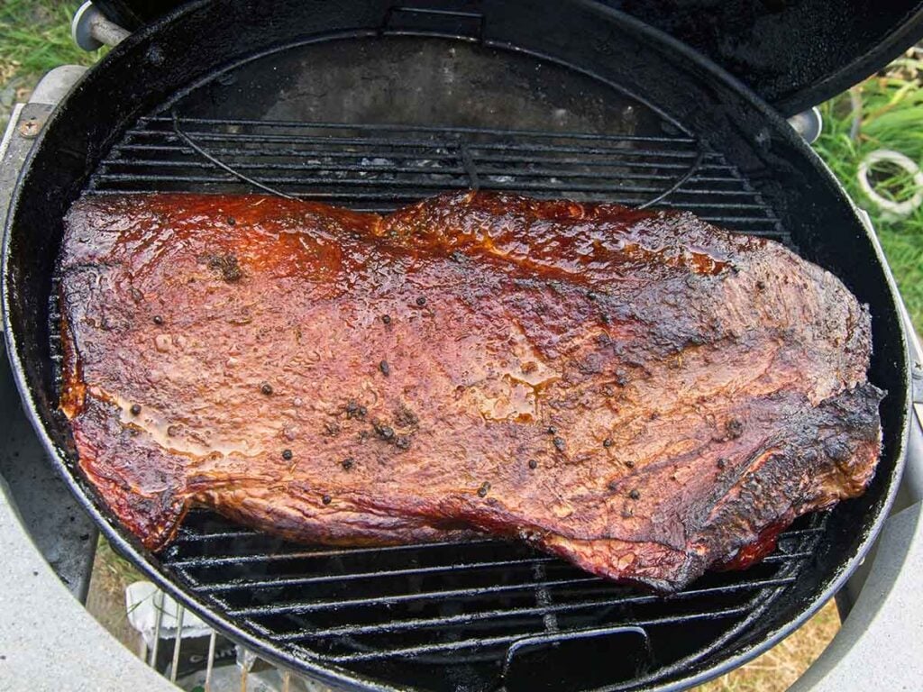 Packer brisket on round charcoal grill.