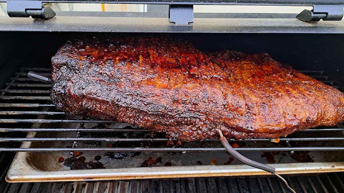 Reddened brisket on grill with thermometers.