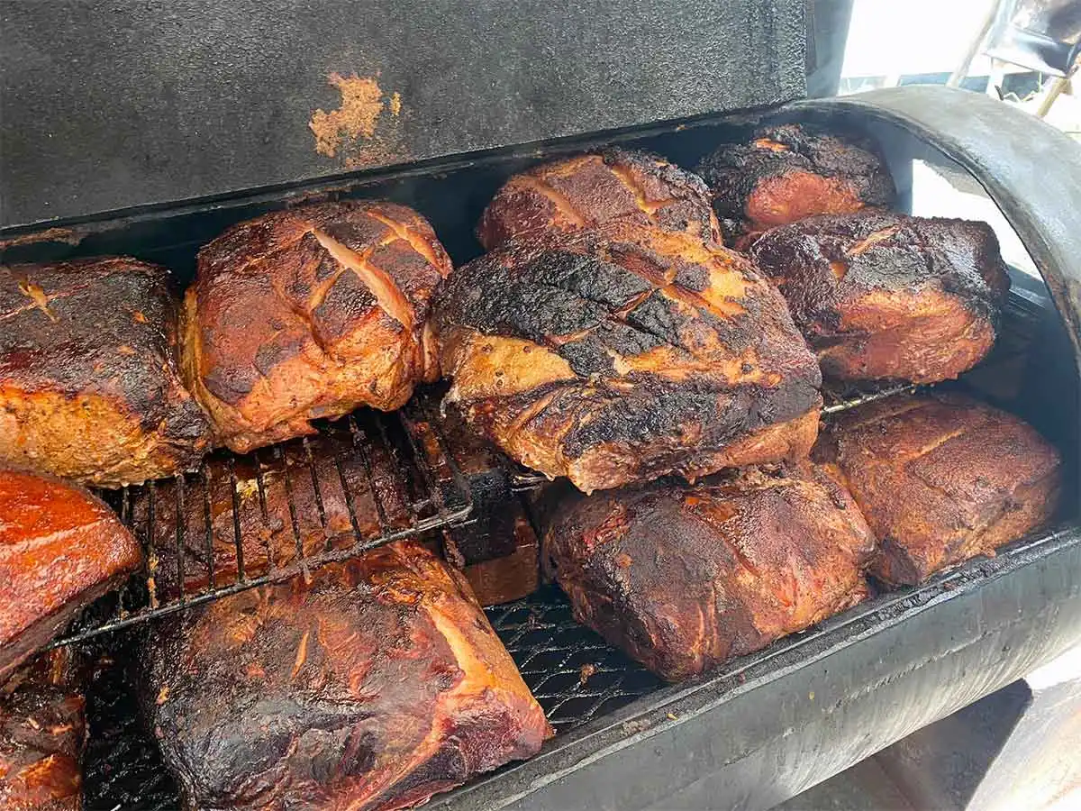 Several rows of butts on an open smoker.