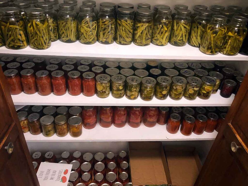 Linen closet shelves full of canned produce in Mason jars.
